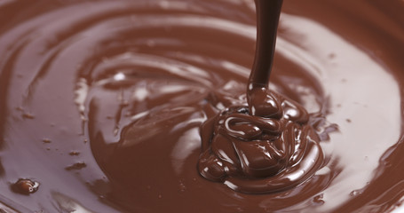 Slow motion of premium dark melted chocolate being poured from spoon in right part of frame, 4k photo