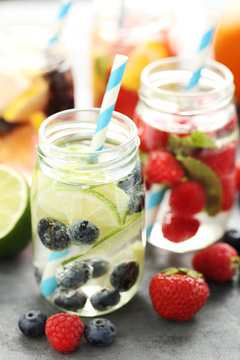 Detox water in bottles with berries on wooden table