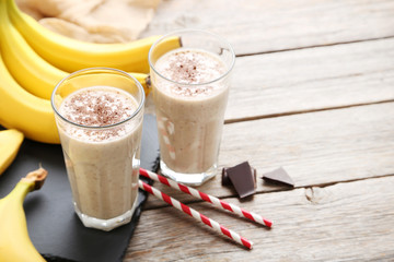 Cocktail with bananas in glasses on grey wooden table