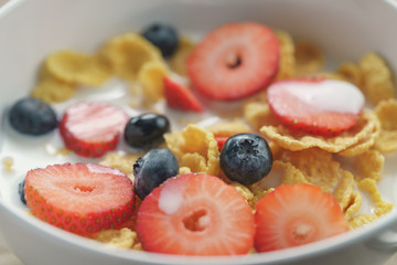 closeup of healthy breakfast with corn flakes and berries in white bowl, slightly toned photo