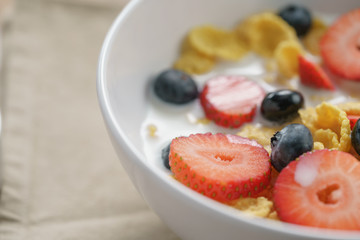 closeup of healthy breakfast with corn flakes and berries in white bowl, slightly toned photo