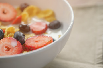 closeup of healthy breakfast with corn flakes and berries in white bowl, slightly toned photo
