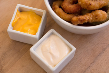 Fried onion ring in bowl with cheese and mayonnaise sauce