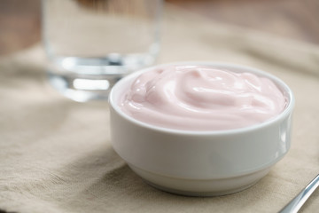 organic strawberry yogurt in white bowl on wood table, shallow focus