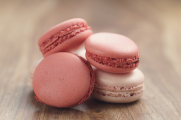 closeup shot of pastel colored macarons mix on wood table, vintage toned photo