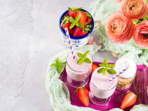 Strawberry milk shake in glasses for romantic breakfast. Summer table setting with ranunculus flowers