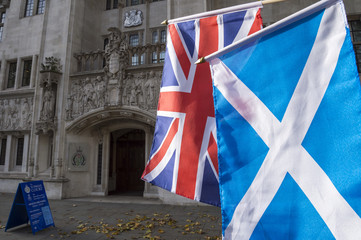 Scottish flag and British Union Jack flag hang together in front of the Supreme Court of the United Kingdom public building