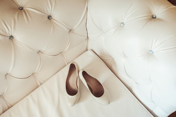 bride's biege shoes on heel on a leather vintage sofa