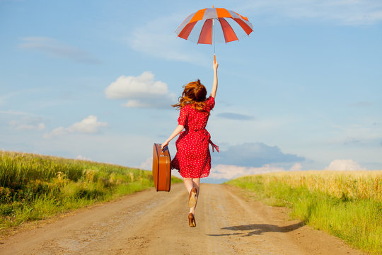 photo of beautiful young woman with suitcase on the road near field background