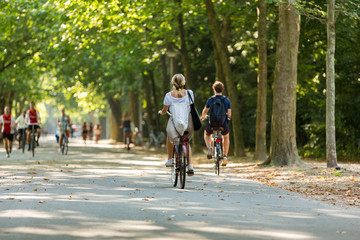 A girl and boy biking in the sunny Amsterdam Vondelpark. The Netherlands. - obrazy, fototapety, plakaty