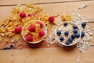 Golden corn flakes, Hercules oat and some berries in a cup on a wooden table.