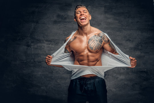 A Man With Tattoo Ripping T Shirt On His Chest.