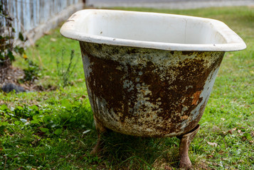 Old rusty bathtub sitting in field