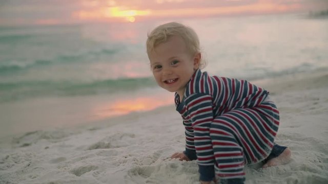 Little baby boy with a toy crawling at the beach