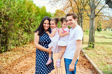 Happy family in the park summer cuddling, laughing and smiling.