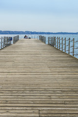 Two girls / young women sitting on pier and making selfies with mobile phone