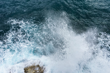 Fototapeta na wymiar Danger ocean wave crashing on rock coast with spray and foam before storm