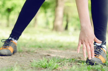 Fototapeta na wymiar Women hands touch the shoes, the concept of stretching or towing hamstring, Exercising in nature