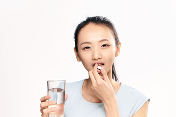 Woman with a pill near the mouth and a glass of water in her hands