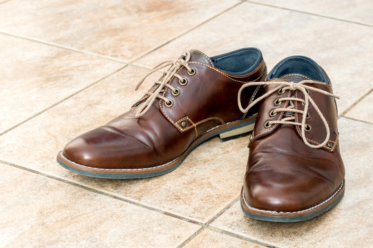 Fashion brown leather men's shoes on a light brown ceramic tiles