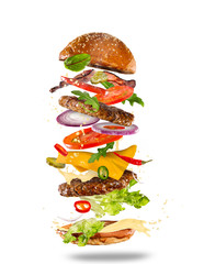 Big tasty burger with flying ingredients. - obrazy, fototapety, plakaty