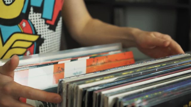 Young woman looking at old vinyl records at flea market