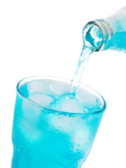 pouring blue soda into glass with ice from bottle