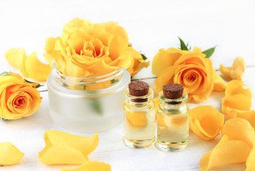 Obraz na płótnie Canvas Rose essential oil for aromatherapy and beauty treatment. Extract in bottles, yellow petals, cosmetic jar with flower.