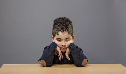 Small student boy sitting on wooden table