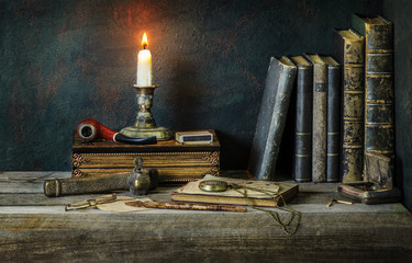 Classic still life with vintage books placed with illuminated candle,old pipe,copper box,pocket watch and old inkwell on rustic wooden background © dinasaeed