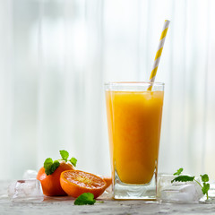 Fresh tangerine juice in glass on white concrete background. Orange fruits with ice, mint. Cold beverage for hot summer day. Copyspace.