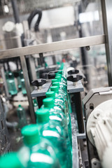 Industrial factory indoors and machinery. Robotic factory line for processing and bottling of pure spring water into canisters and bottles. Selective focus. Short depth of field.