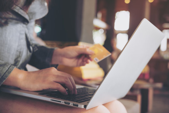 A business woman holding credit card while using laptop in coffee shop