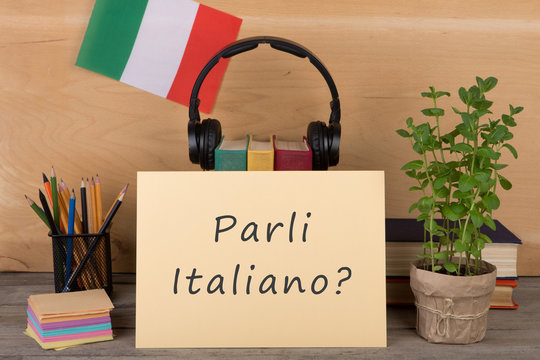 paper with text "parli italiano?", flag of the Italia, books, headphones, pencils
