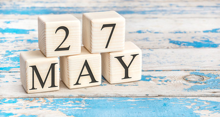 May 27th. Wooden cubes with date of 27 May on old blue wooden background.