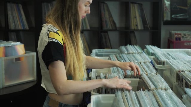 Young woman looking at old vinyl records at flea market