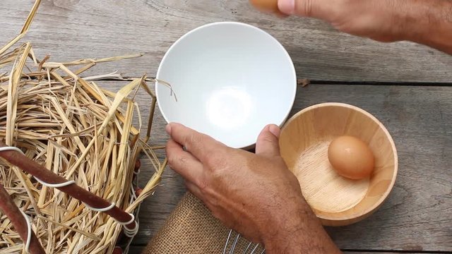 man hands breaking an egg to separate and egg shells at background