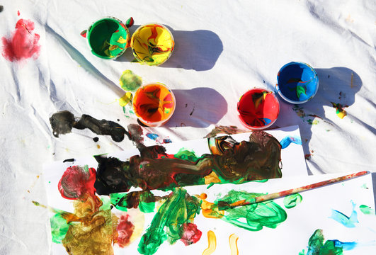 pinturas y pincel sobre una tela blanca manchada por ni&ntilde;os