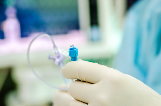 The doctor holds a cock for the catheter, on which there is a droplet of physiological solution.