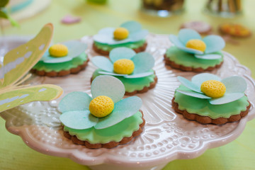cookies decorated with delicate flowers in green spring colors on a white plate. Elements of the festive candy bar