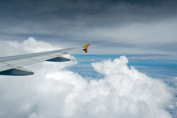 Wing of an airplane flying above the clouds see through the window. Business concept.