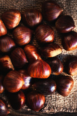 Raw Chestnuts  on old wooden table with copy space, close up. Beautiful chestnuts top view.