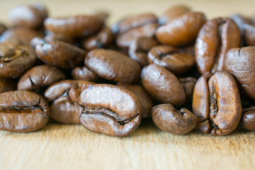 Coffee beans on wooden table closeup.