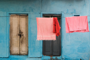 Pink clothes hanging in front of bright blue texture background with doors in Bangalore, India