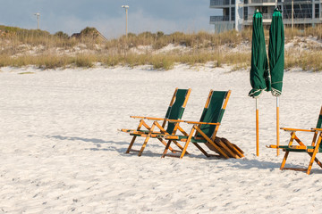 Beach chairs and umbrellas on white sandy beach.