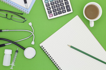 Stethoscope with pencil, white paper,calculator,coffee cup,glasses,bottle of medicine and syringe on office desk.