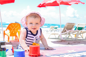 Funny baby girl playing on the beach.