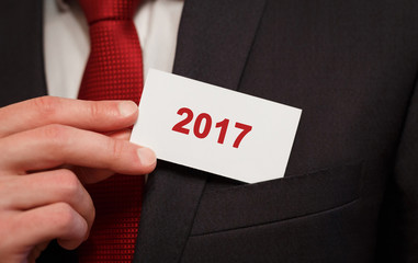 Businessman putting a card with text 2017 in the pocket