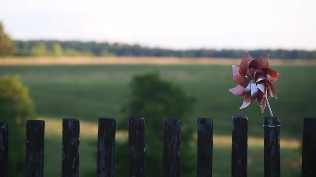 Spinning pinwheel attached to old wooden fence.