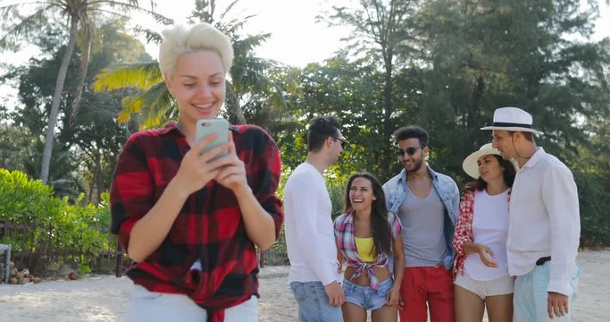 Girl Use Cell Smart Phone Chatting Online Over Young People Group Talking In Tropical Palm Tree Park Slow Motion 60